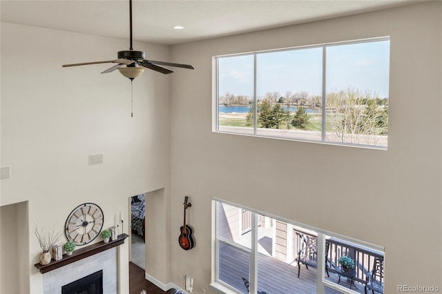 living area featuring a glass covered fireplace, ceiling fan, and a water view