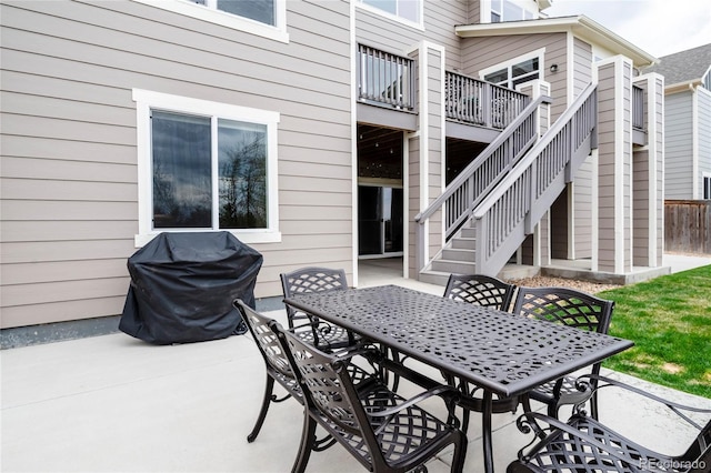 view of patio with outdoor dining space, area for grilling, stairs, and a deck
