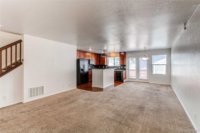 19043 E 58th Ave, Denver, CO 80249 - kitchen with black appliances, open floor plan, carpet floors, a kitchen island, and a textured ceiling