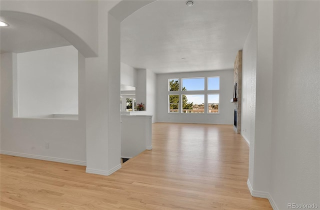 interior space featuring baseboards, arched walkways, and wood finished floors