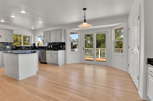 kitchen featuring dishwasher, dark countertops, backsplash, and light wood-style flooring