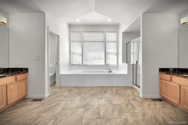 full bathroom featuring toilet, a bath, a textured ceiling, a shower stall, and two vanities