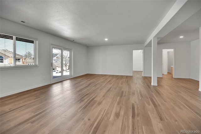 unfurnished living room featuring light wood finished floors, recessed lighting, visible vents, a textured ceiling, and baseboards