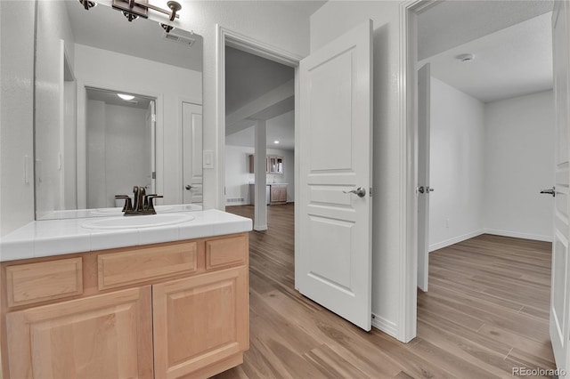 bathroom featuring visible vents, baseboards, wood finished floors, and vanity