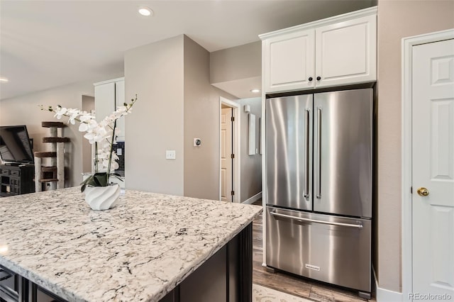 9458 S Hackberry Ln, Highlands Ranch, CO 80129 - kitchen featuring high end fridge, white cabinetry, light stone counters, light wood-type flooring, and a kitchen island
