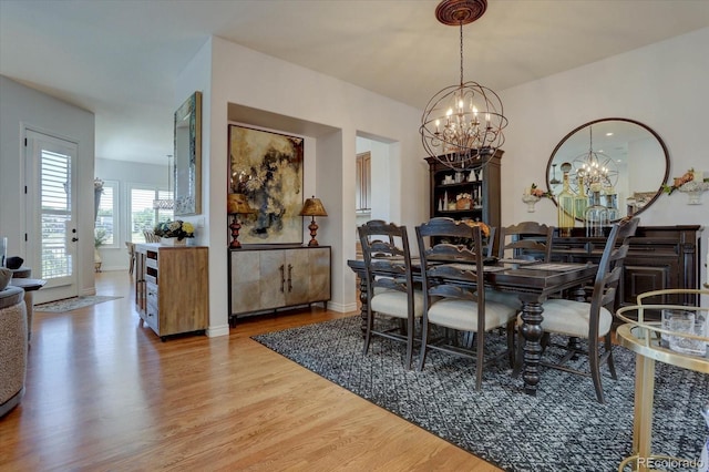 dining room with light hardwood / wood-style floors and a notable chandelier