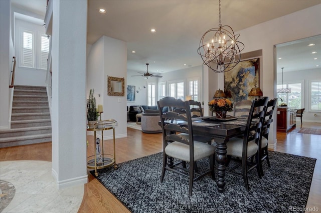 dining room with light hardwood / wood-style flooring and ceiling fan with notable chandelier