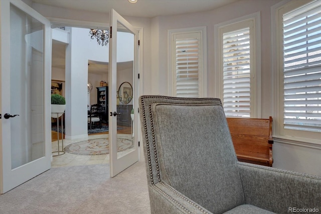 interior space with a chandelier, french doors, light colored carpet, and a healthy amount of sunlight