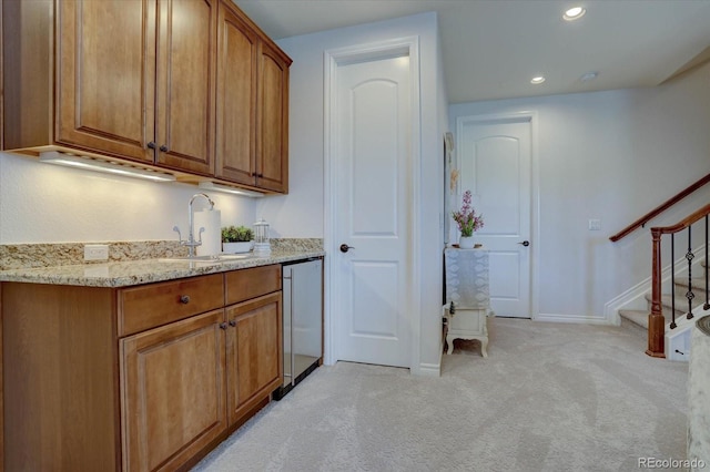 kitchen featuring dishwasher, light colored carpet, light stone countertops, and sink