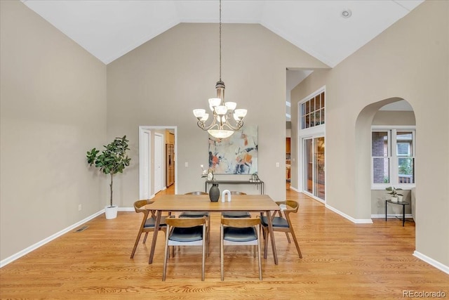 dining area featuring high vaulted ceiling, light hardwood / wood-style flooring, and a chandelier