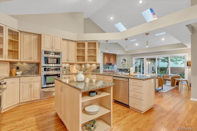 kitchen with backsplash, stainless steel appliances, a center island, and a skylight