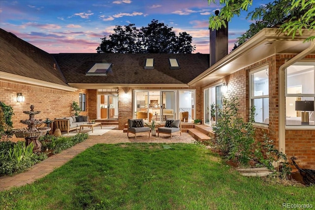 back house at dusk featuring a lawn, a patio area, and an outdoor hangout area