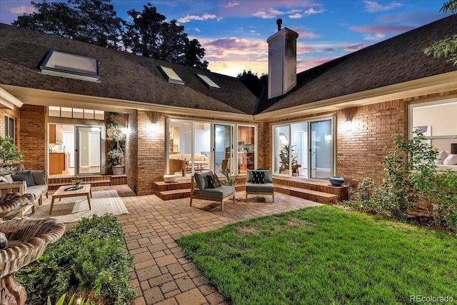 back house at dusk with a yard and a patio