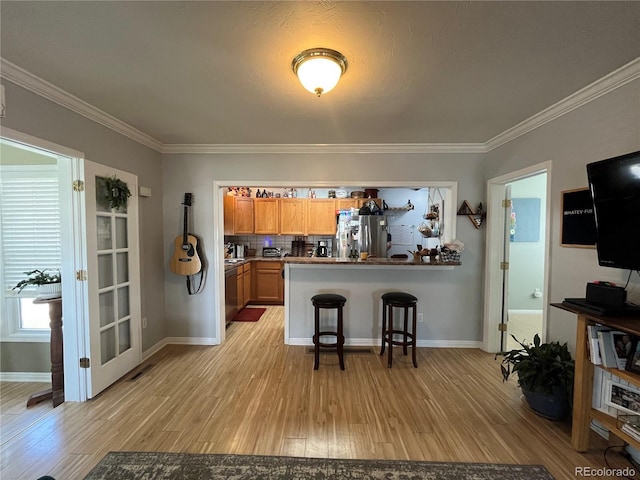 790 4th St, Limon, CO 80828 - kitchen featuring freestanding refrigerator, light wood finished floors, a peninsula, a kitchen breakfast bar, and ornamental molding