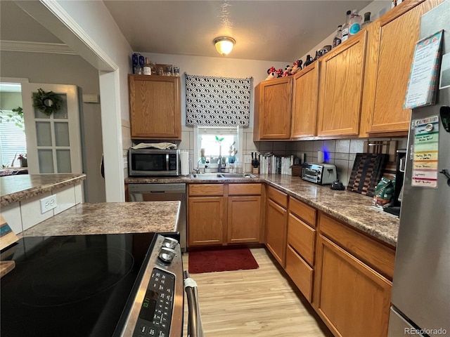 790 4th St, Limon, CO 80828 - kitchen featuring appliances with stainless steel finishes, a sink, light wood finished floors, backsplash, and crown molding
