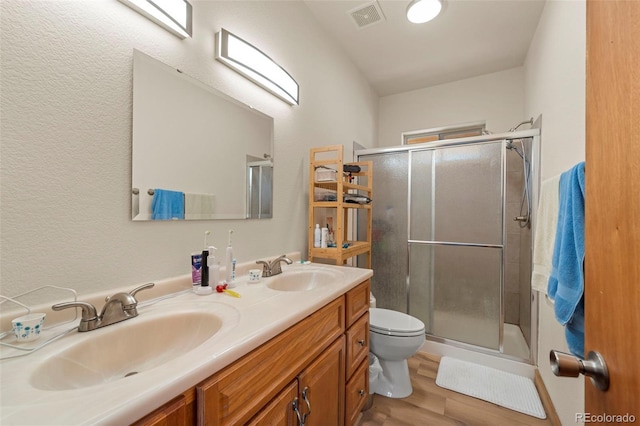 bathroom with a sink, a stall shower, toilet, and visible vents