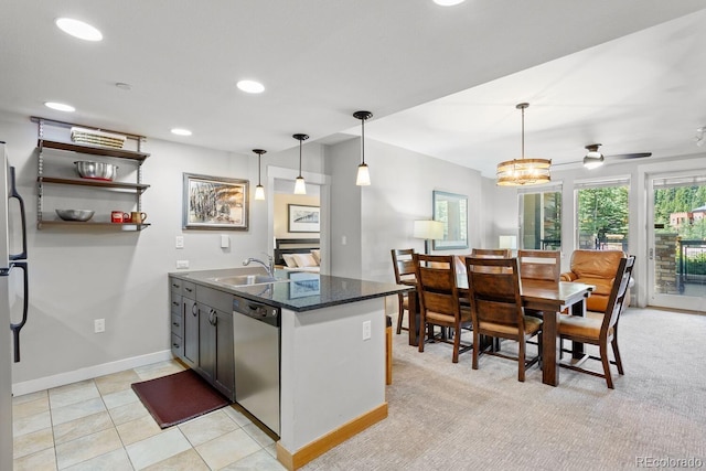 kitchen with kitchen peninsula, appliances with stainless steel finishes, ceiling fan with notable chandelier, sink, and hanging light fixtures