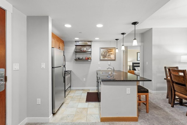 kitchen featuring sink, stainless steel fridge, dark stone counters, pendant lighting, and a breakfast bar