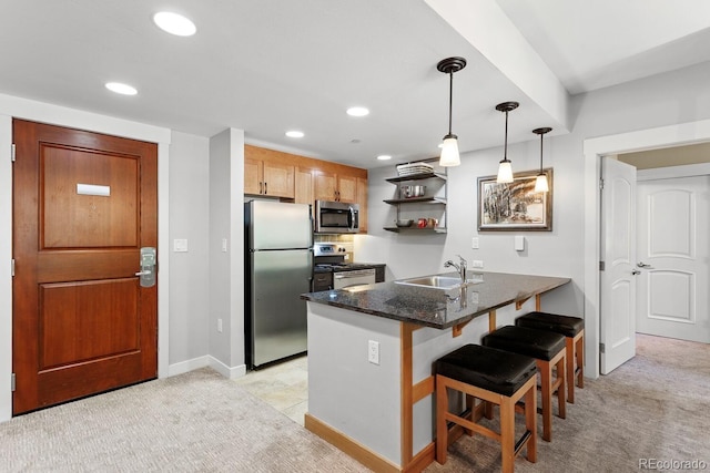 kitchen with sink, hanging light fixtures, a kitchen breakfast bar, kitchen peninsula, and appliances with stainless steel finishes