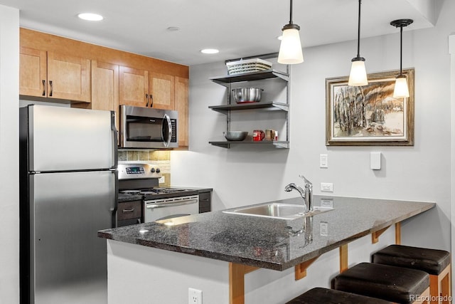 kitchen featuring appliances with stainless steel finishes, backsplash, a breakfast bar, sink, and hanging light fixtures