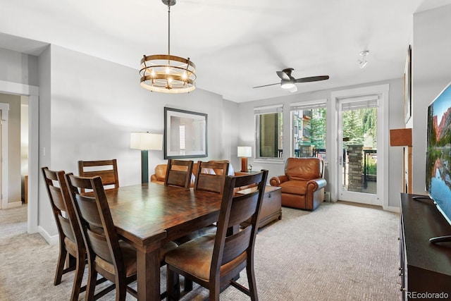 dining area featuring ceiling fan with notable chandelier and light carpet