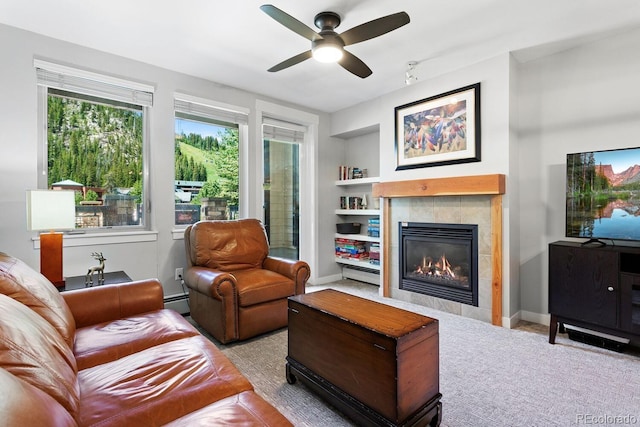 carpeted living room featuring ceiling fan, baseboard heating, a fireplace, and built in shelves