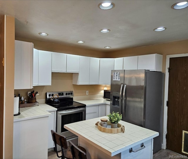 2034 S Truckee St, Aurora, CO 80013 - kitchen with appliances with stainless steel finishes, tile counters, white cabinetry, recessed lighting, and a center island