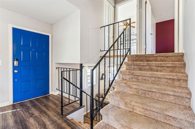 entryway featuring baseboards, a ceiling fan, wood finished floors, and stairs