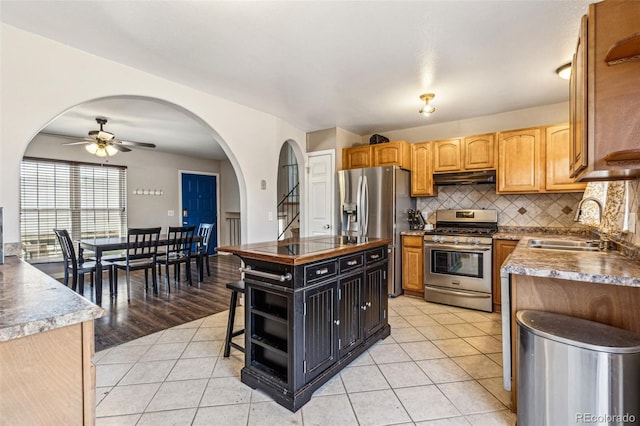 kitchen with under cabinet range hood, light tile patterned floors, appliances with stainless steel finishes, and a kitchen island