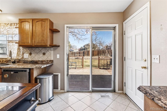 kitchen with dishwasher, dark countertops, light tile patterned flooring, and decorative backsplash