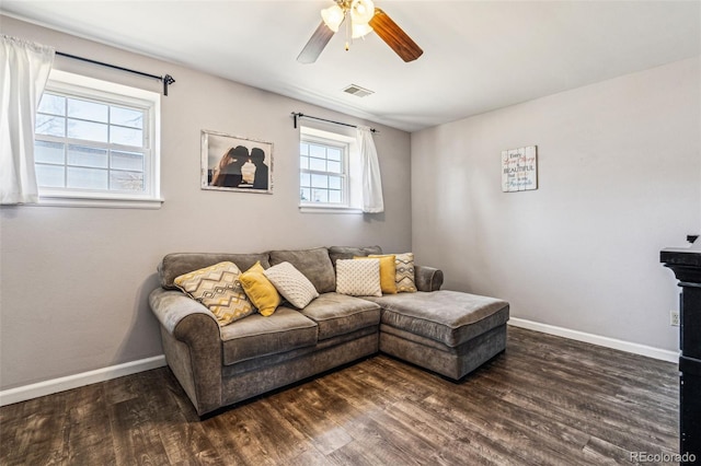 living room with visible vents, baseboards, dark wood finished floors, and a ceiling fan