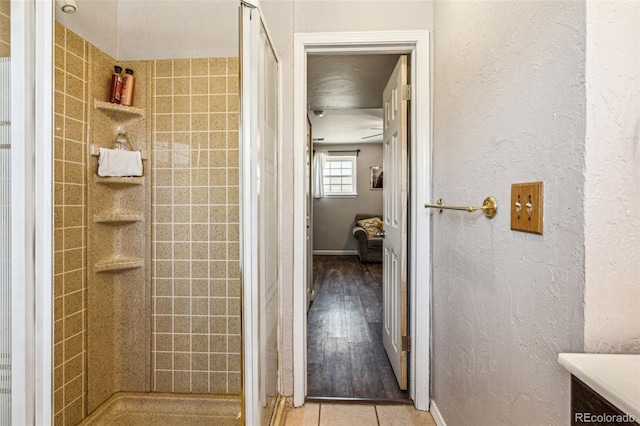 full bath featuring tile patterned flooring, a textured wall, and a stall shower