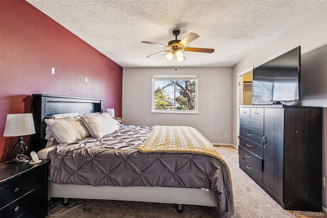 carpeted bedroom with ceiling fan, baseboards, and a textured ceiling