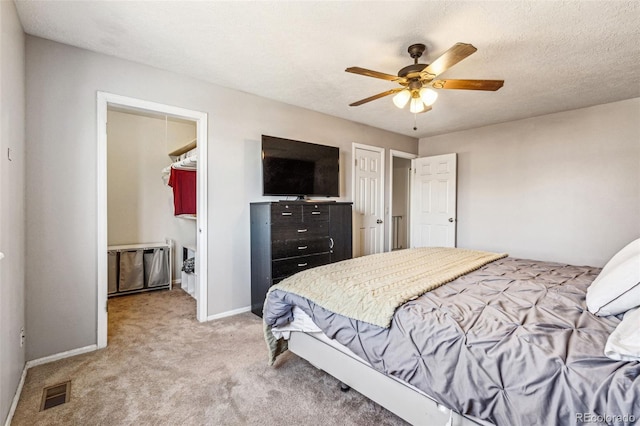 bedroom featuring baseboards, visible vents, ceiling fan, a textured ceiling, and light carpet