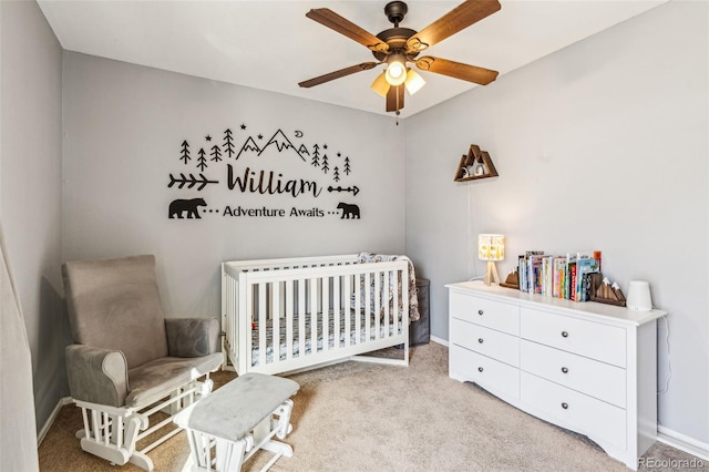 bedroom featuring baseboards, a crib, carpet, and a ceiling fan