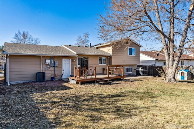 rear view of property featuring a yard, roof with shingles, a wooden deck, and fence