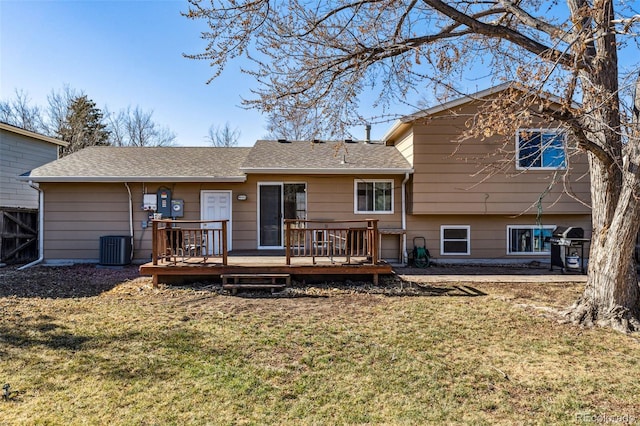 back of property with a shingled roof, central air condition unit, a yard, and a wooden deck