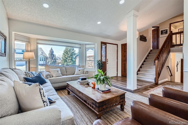 living room with decorative columns, stairs, wood finished floors, and recessed lighting