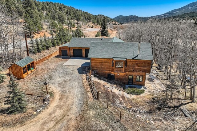 44 Forest Ridge Cir, Bailey, CO 80421 - view of front of house with driveway, roof with shingles, an outbuilding, and a mountain view
