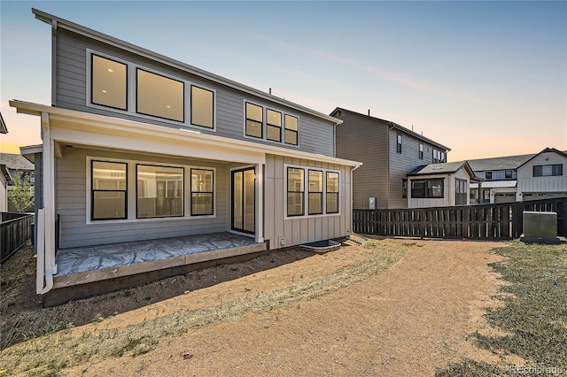 back of property at dusk with board and batten siding and fence