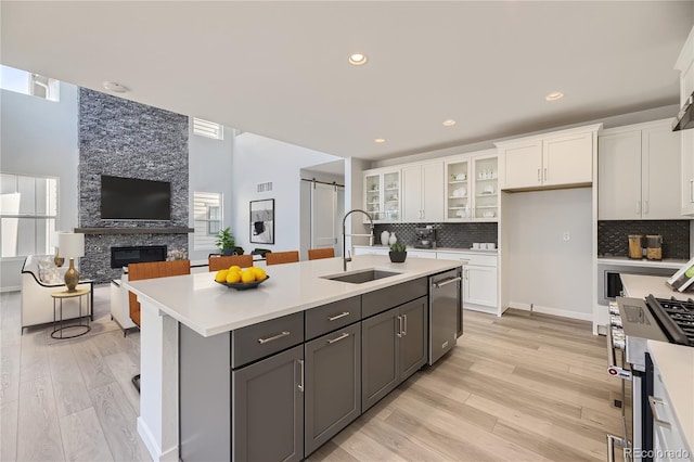 kitchen featuring light countertops, a barn door, glass insert cabinets, white cabinets, and a sink