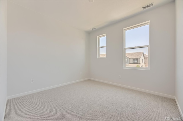 spare room with carpet floors, visible vents, and baseboards