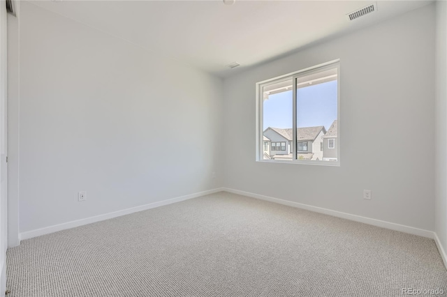 empty room with carpet flooring, visible vents, and baseboards