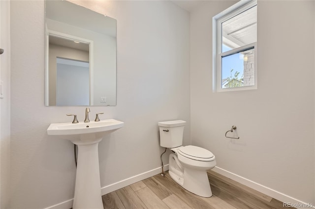 half bath featuring baseboards, toilet, and wood finished floors