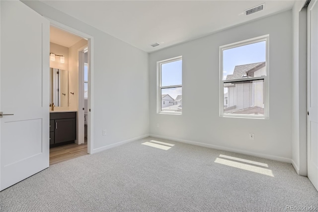 unfurnished bedroom with light carpet, baseboards, and visible vents