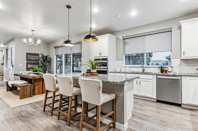 kitchen with plenty of natural light, a kitchen island, decorative light fixtures, and appliances with stainless steel finishes