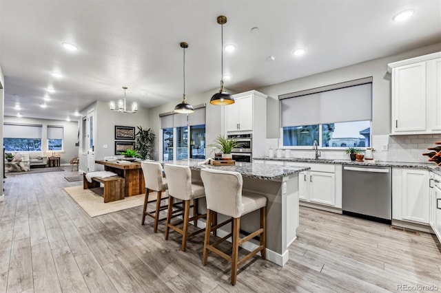 kitchen featuring appliances with stainless steel finishes, a kitchen island, plenty of natural light, and pendant lighting