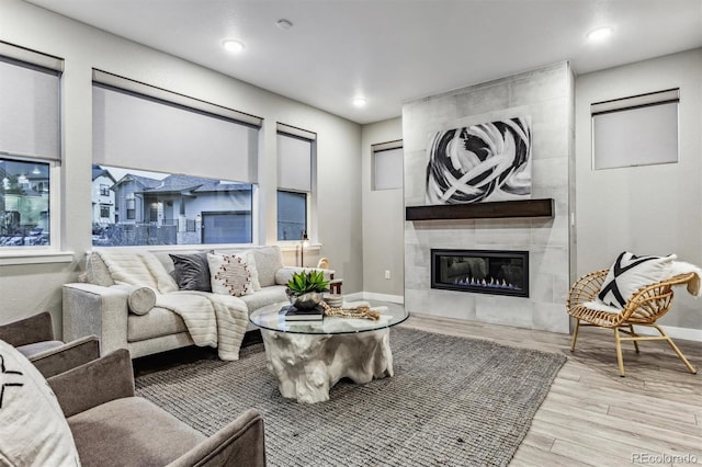 living room featuring a tiled fireplace and light hardwood / wood-style flooring