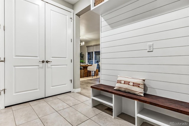 mudroom with light tile patterned flooring and wooden walls