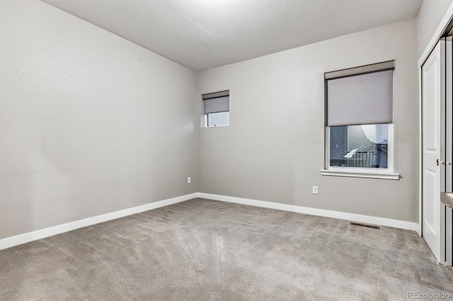 carpeted empty room with a textured ceiling